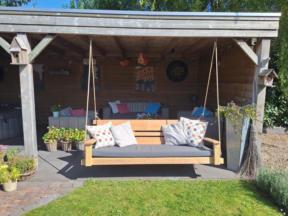 Schommelbank van Douglashout bij zonsondergang onder veranda