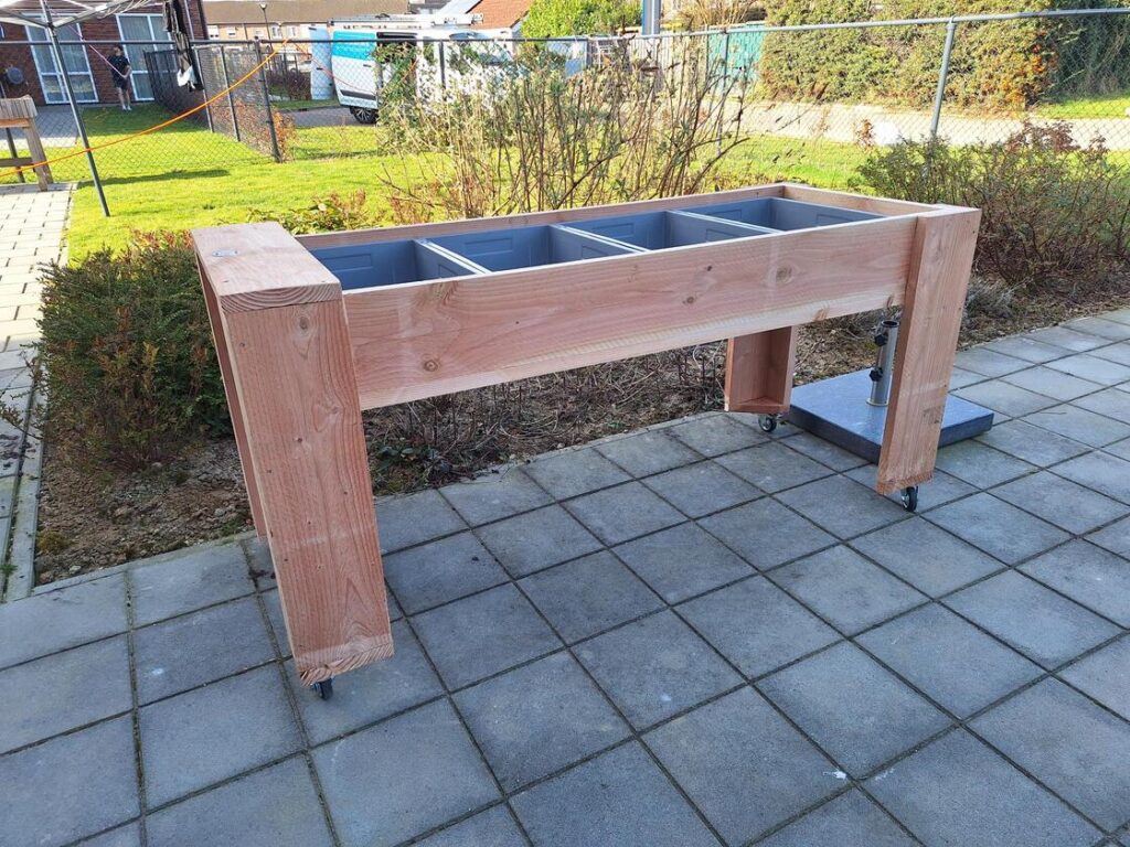 Bewoners tuinieren aan een verrijdbare kweektafel in een kleinschalige woonsetting voor mensen met dementie in Sittard.