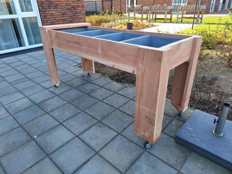 Bewoners verzorgen kruiden en plantjes aan een mobiele kweektafel in de dementiezorg.