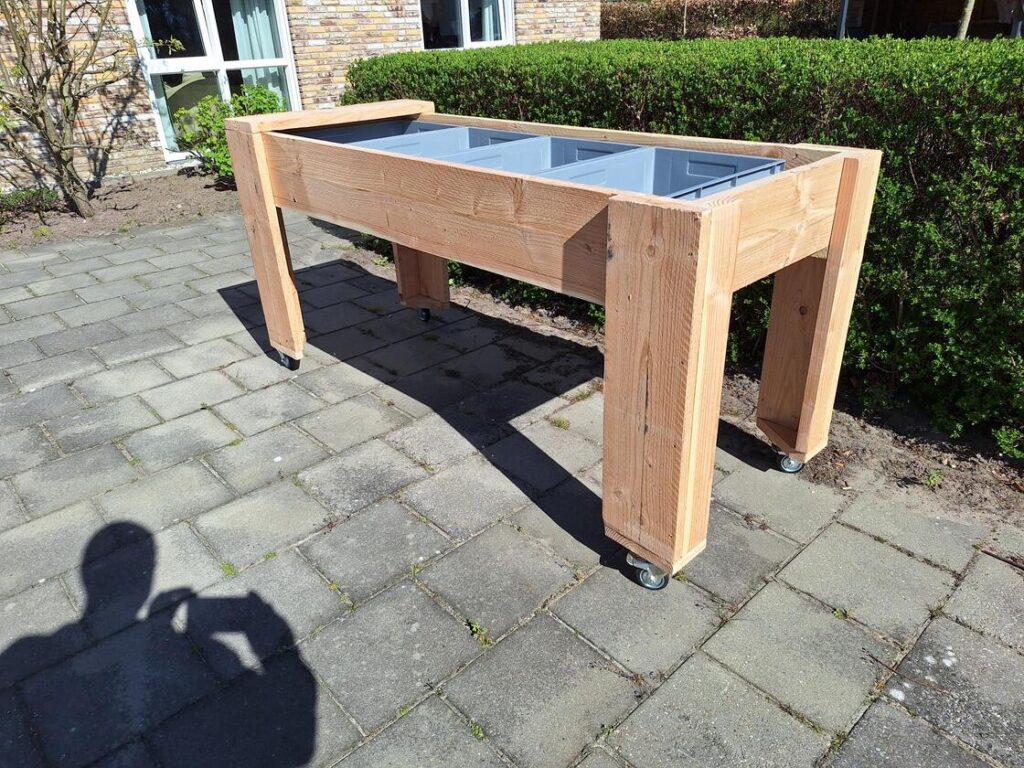 Verrijdbare kweektafel met bewoners die planten verzorgen in woonhuis voor mensen met dementie.