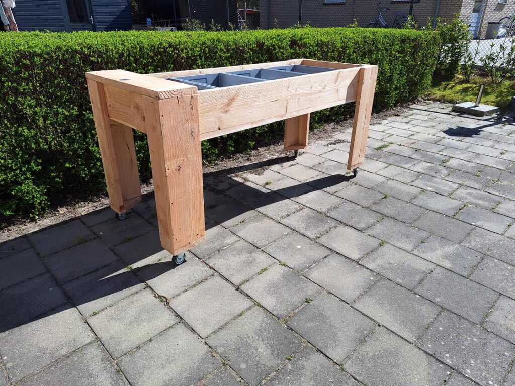 Bewoner bezig met tuinieren aan verrijdbare kweektafel in woonhuis voor mensen met dementie.