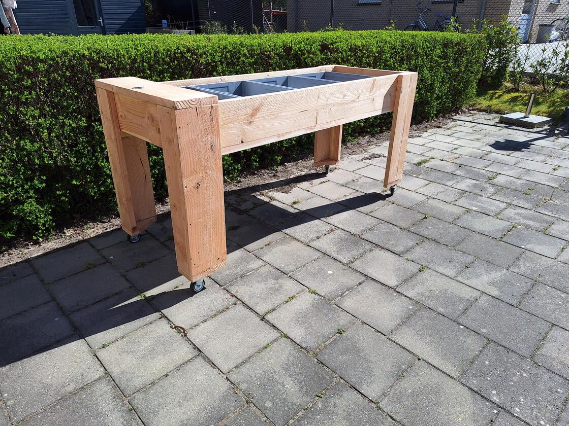 Bewoner bezig met tuinieren aan verrijdbare kweektafel in woonhuis voor mensen met dementie.