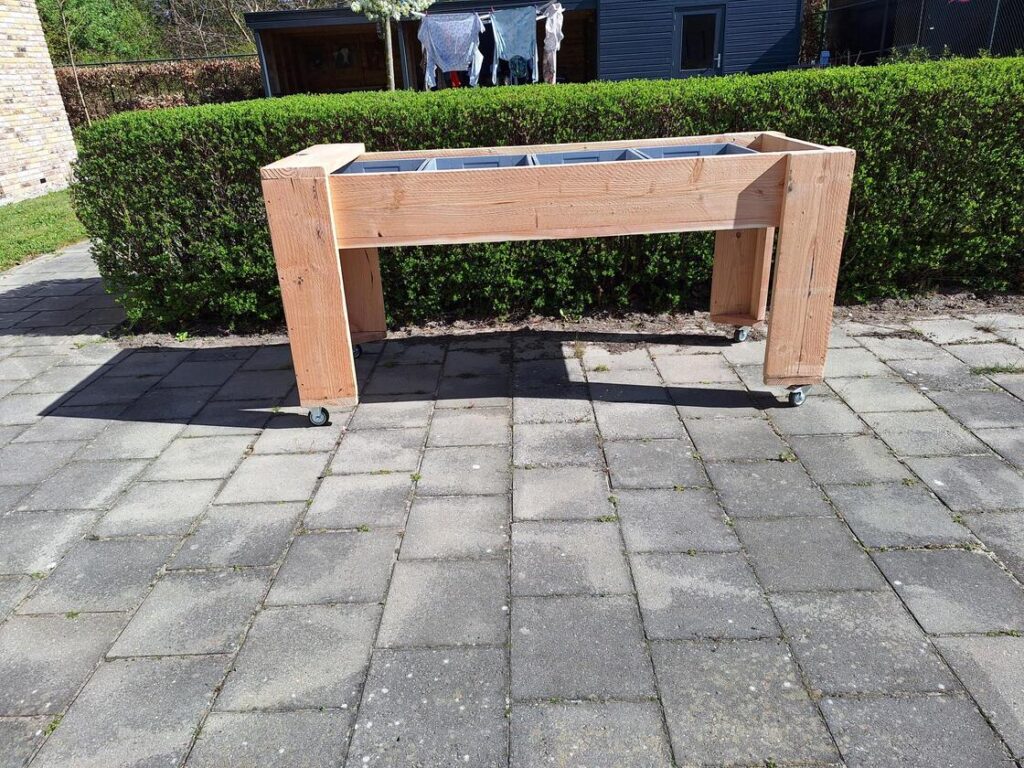 Groep bewoners geniet samen van tuinieren aan verrijdbare kweektafel in Steenwijk.