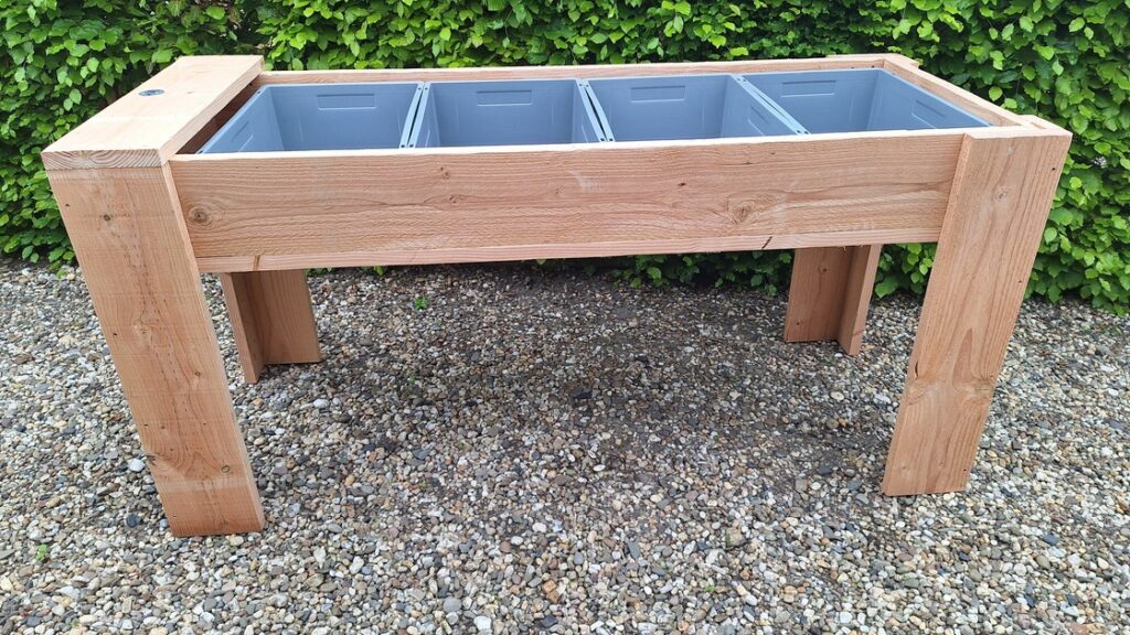 Houten kweektafel in de tuin met planten en kruiden Titel: